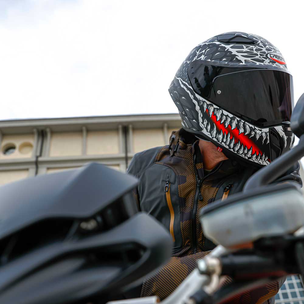 side view of a biker wearing his full face motorbike lid with teeth and skull design and red accents