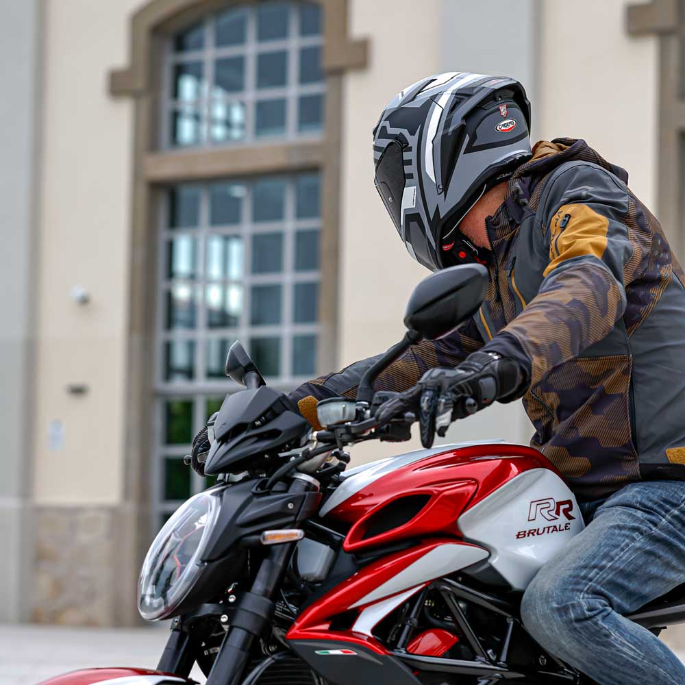 biker riding motorbike wearing black motorcycle gloves and black and grey motorbike helmet