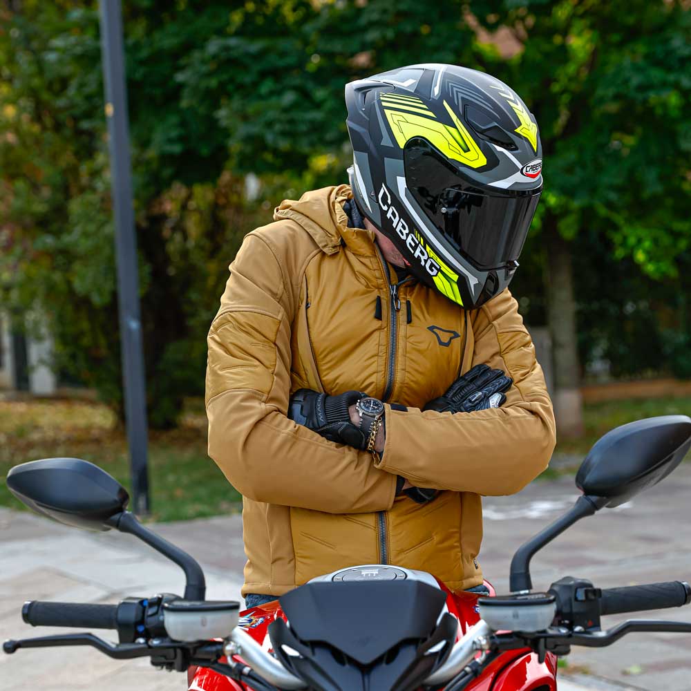 side view of biker wearing black and yellow full face motorbike helmet with tinted smoke visor on a motorcycle