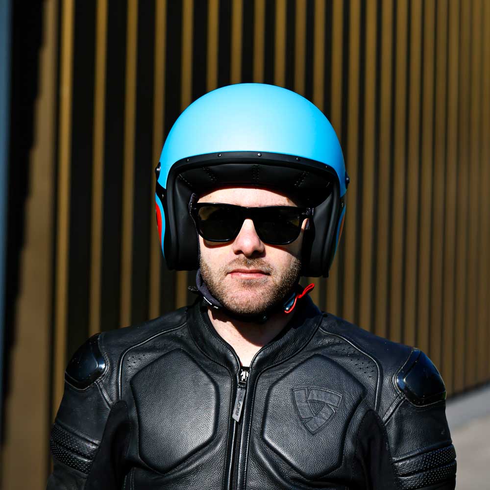 biker wearing black leather race suit with matte blue open face motorbike helmet with orange detail