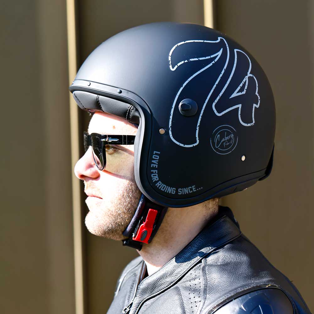 side view of biker wearing black open face motorbike helmet with shades and chin strap fastened