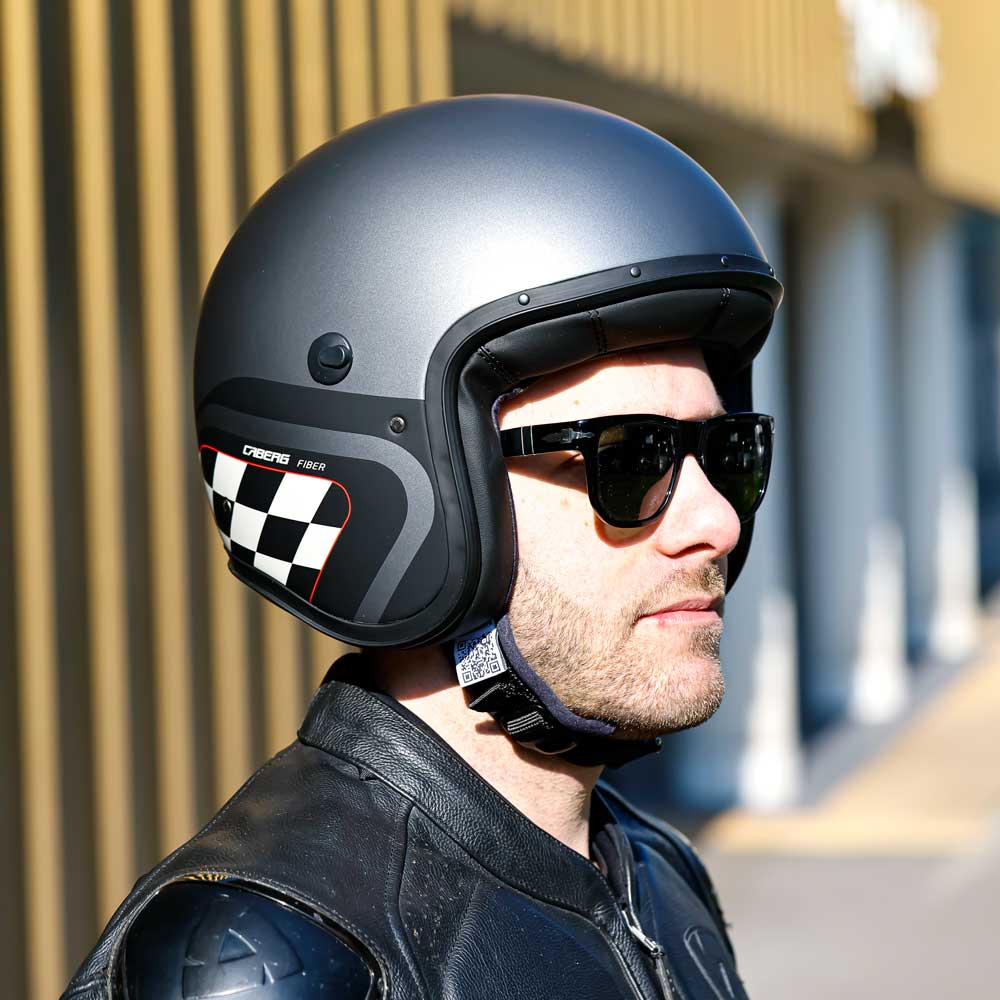 side of biker wearing black open face motorcycle helmet with black and white checkers design