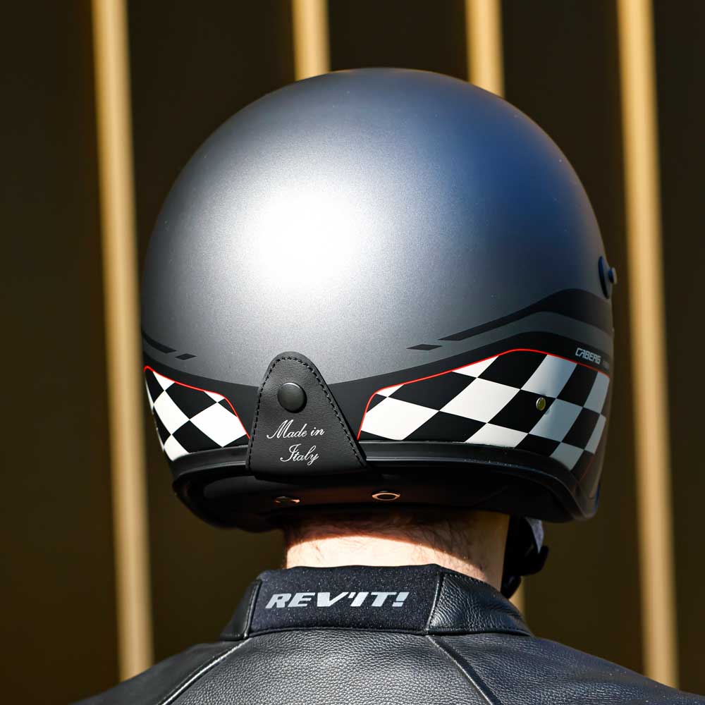 back of biker wearing gun metal grey motorbike helmet with black and white chequered design