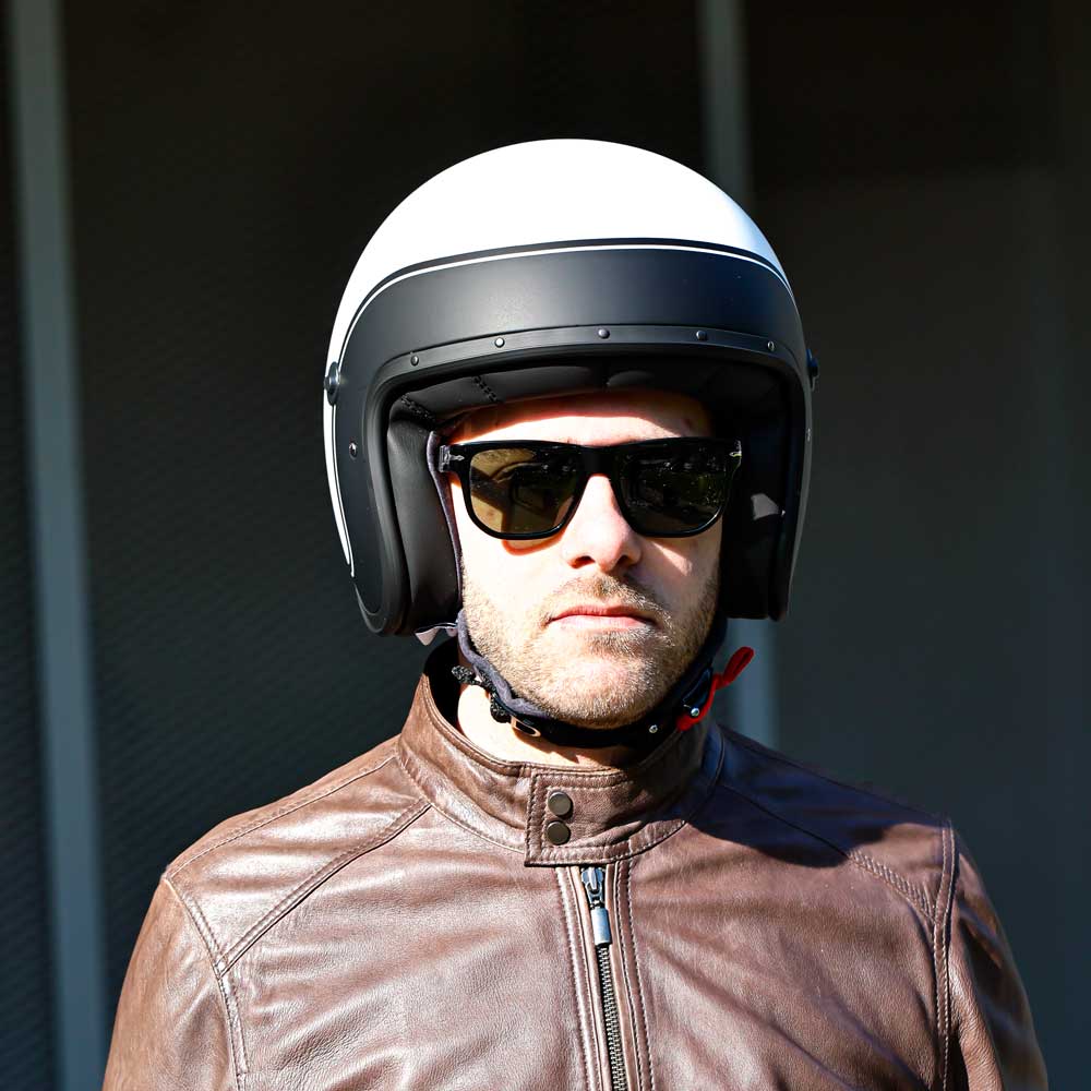 biker wearing brown leather jacket for men paired with a matte white and black open face helmet