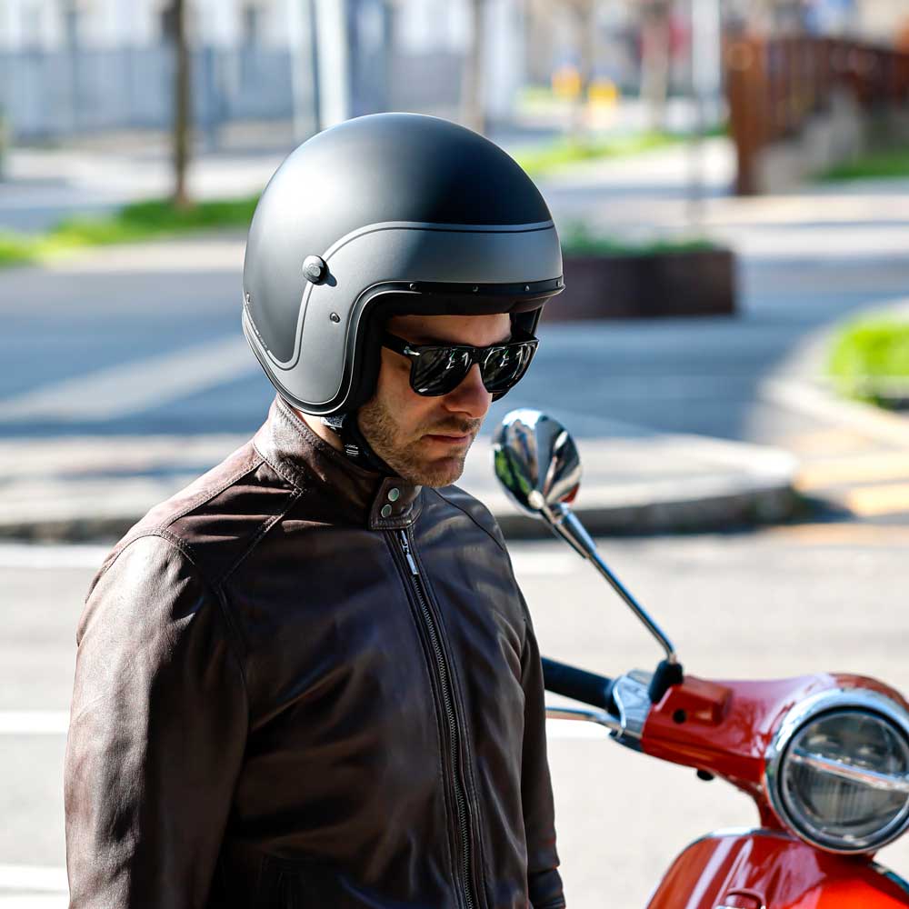 biker stood next to his red motorbike wearing black matte open face helmet with gunmetal design