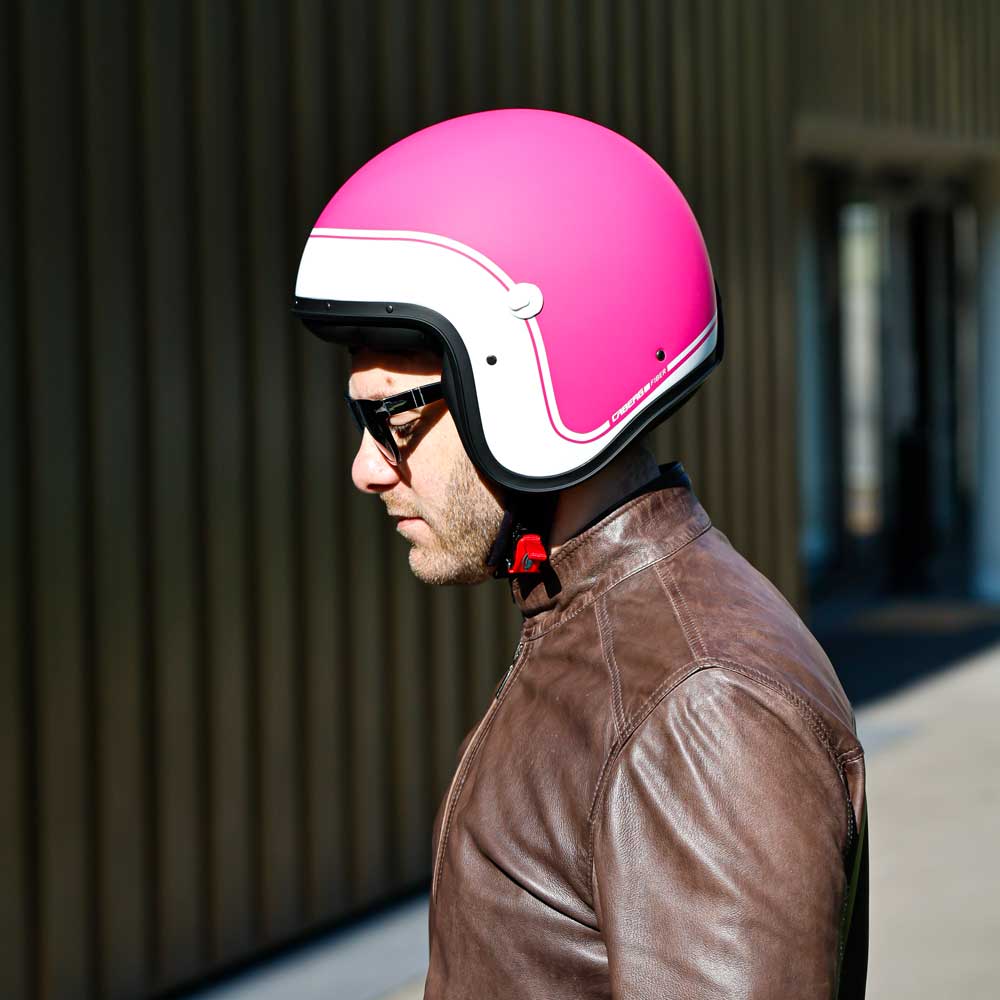 biker wearing brown leather jacket for men with matte pink and white motorbike helmet