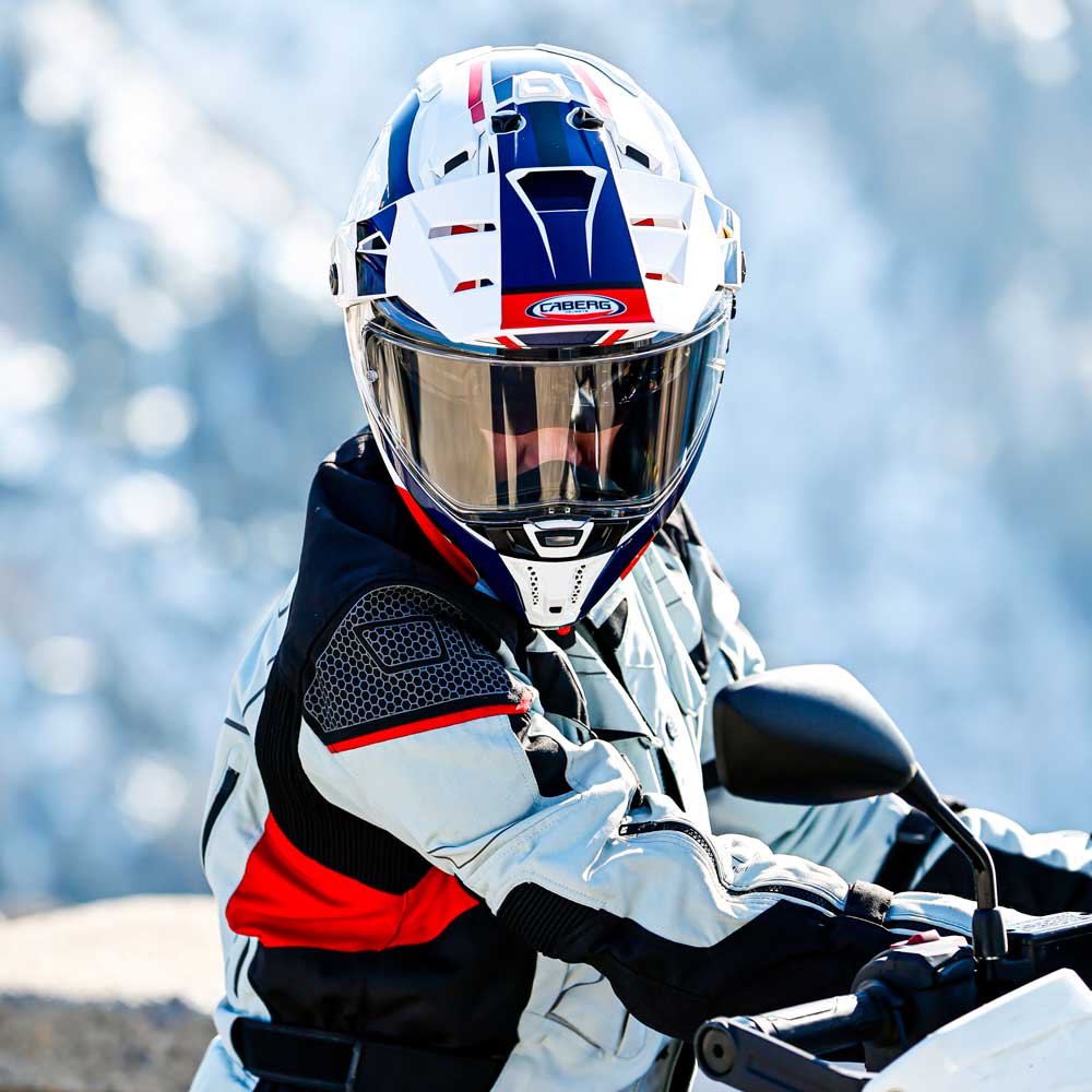 biker wearing white and red motorcycle gear including full face helmet on bike ride in the mountains