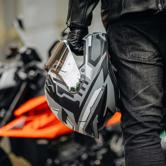 biker holding caberg motorcycle helmet with orange and black motorbike