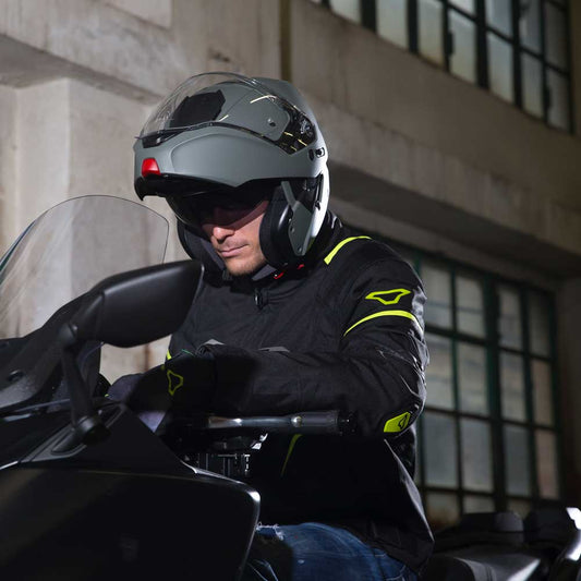 biker riding a motorbike wearing a dark grey flip up motorbike helmet by caberg