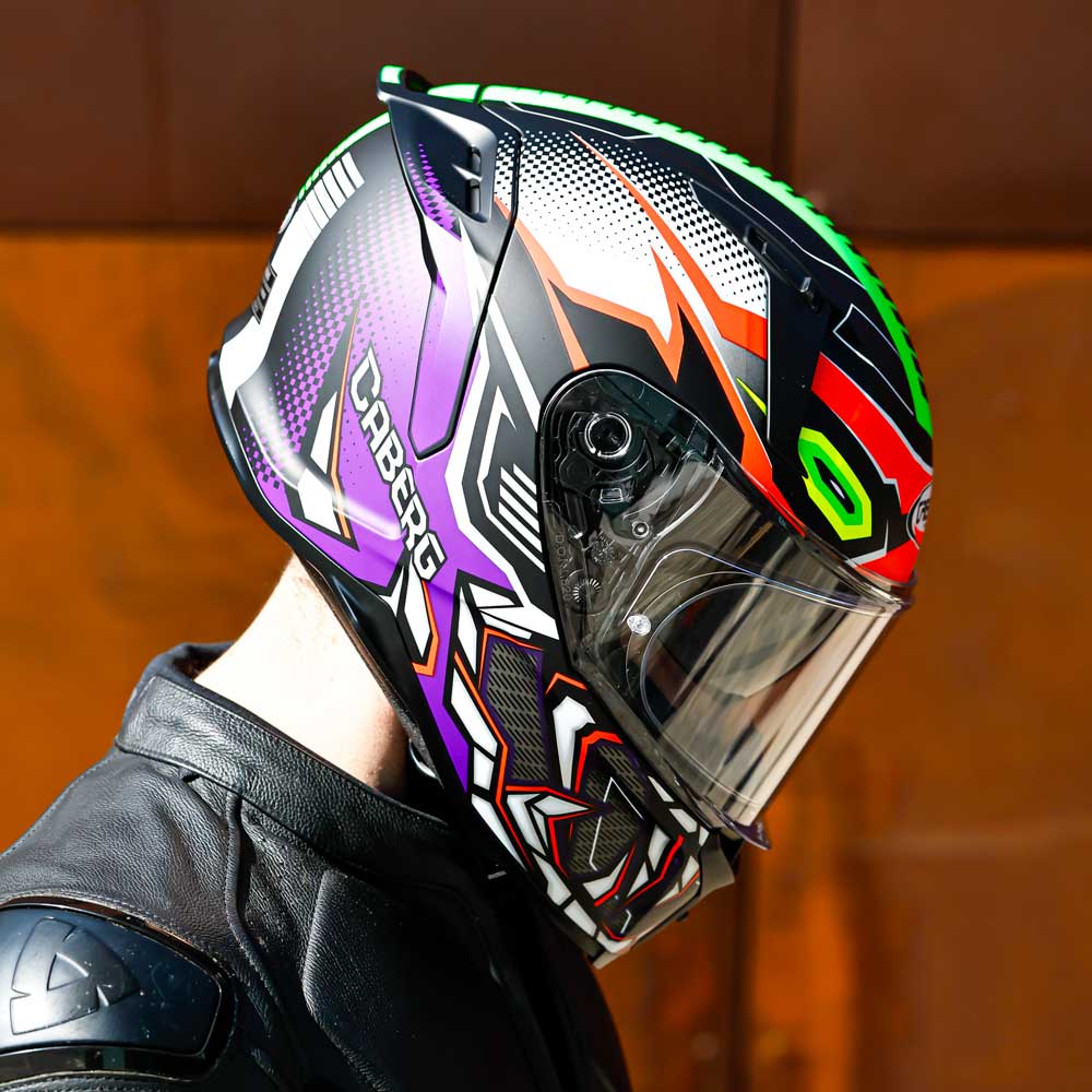 biker with his head tilted down wearing the purple orange and green caberg gurkha full face motorbike helmet