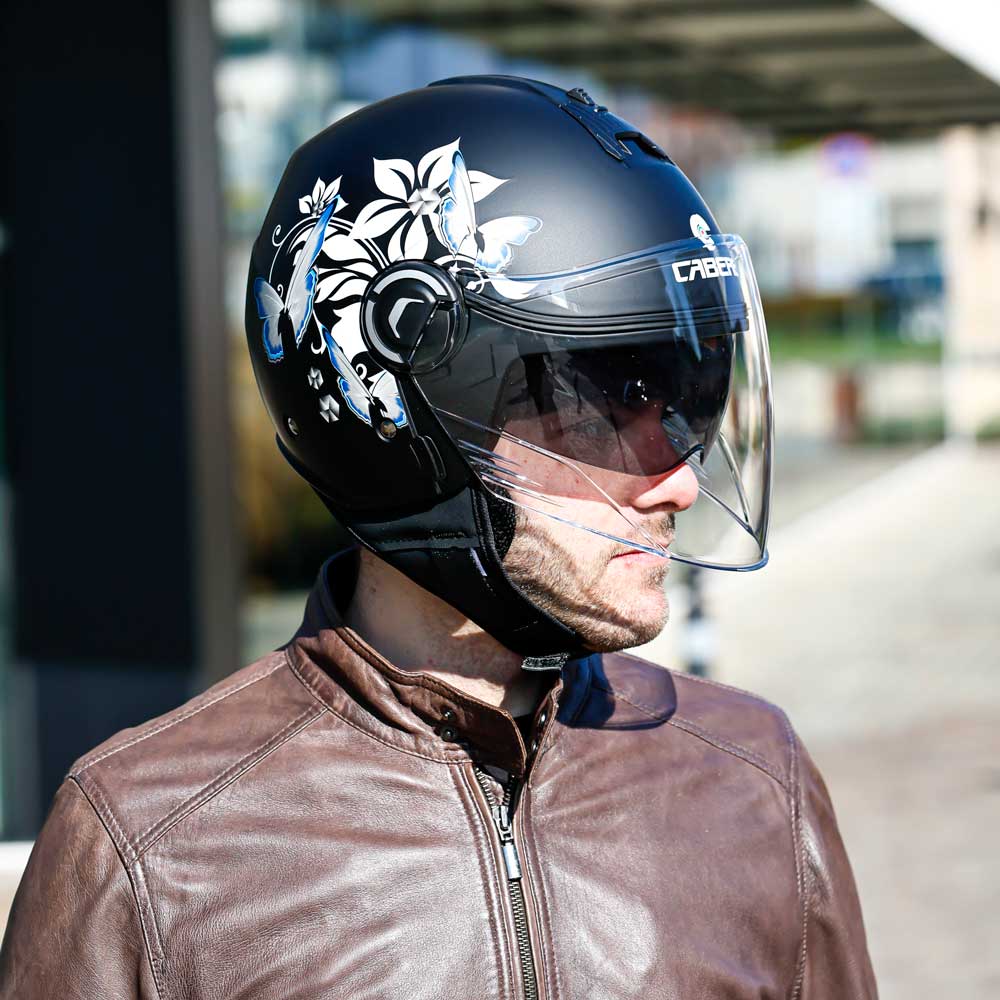 A man looking left while wearing the helmet, with both visors down, displaying the clean helmet lines and side floral detailing.