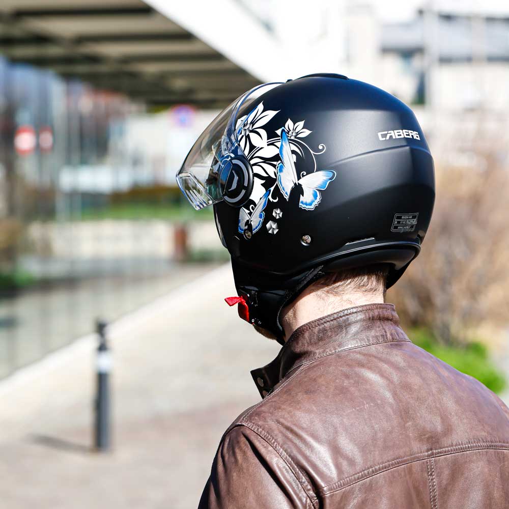 Rear view of a man wearing the helmet with the clear visor up, showing the full floral design across the back.